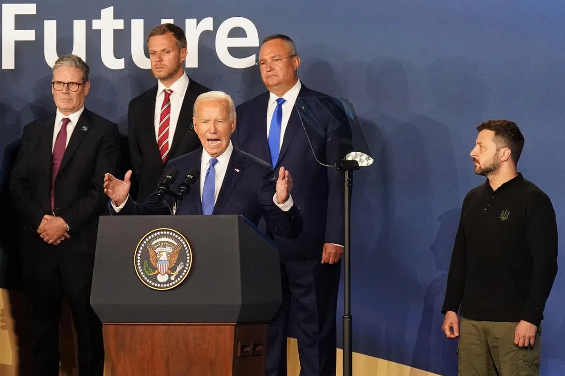 Ukraine's President Volodymyr Zelensky (R) listens as US President Joe Biden (C) speaks during the closing ceremony at the NATO 75th anniversary summit at the Walter E. Washington Convention Center in Washington, DC on July 11, 2024. (Photo by Stefan Rousseau / POOL / AFP)