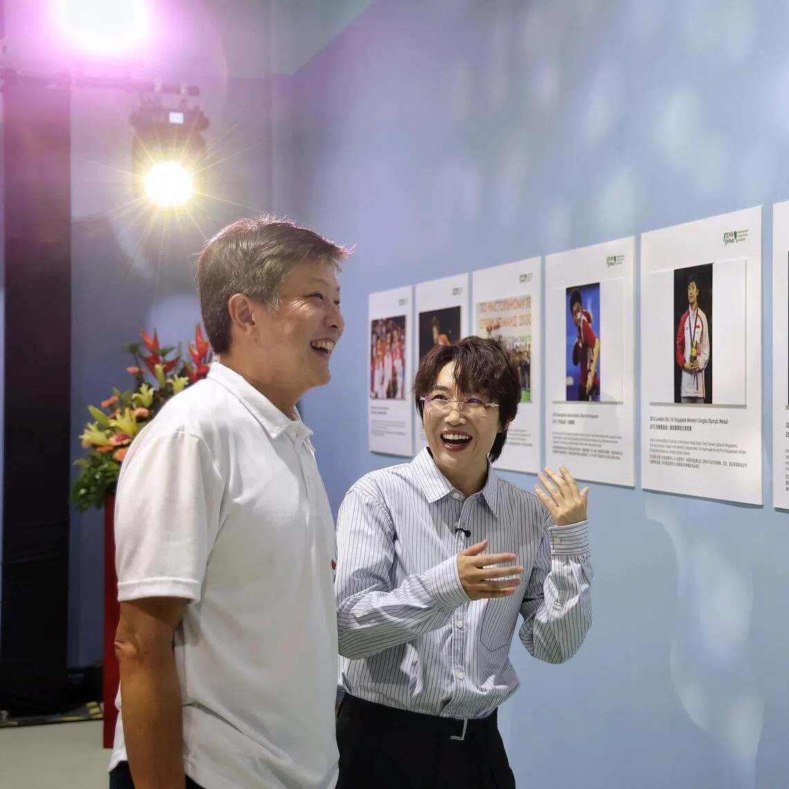 Singapore's Olympic medalist Feng Tianwei taking Jalan Kayu Member of Parliament Ng Chee Meng on a tour of a photo wall of her achievements during the grand opening of the Feng Tianwei International Table Tennis Academy at The Sports Arina @ Jalan Kayu.