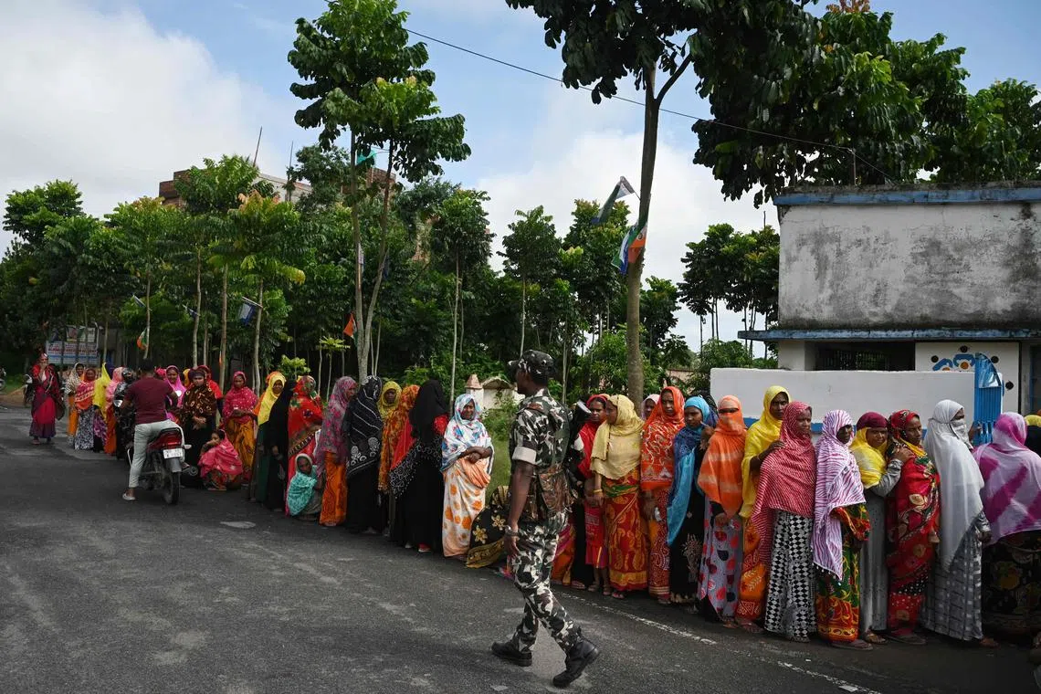 A paramilitary soldier stands guard as people queue outside a polling station to cast their vote in West Bengal's 'Panchayat' or local elections.
