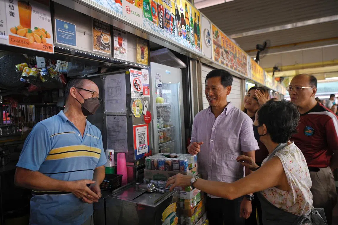Minister for Health Ong Ye Kung (centre) and Advisor to Ang Mo Kio GRC Grassroots Organisation Nadia Ahmad Samdin (background) speak to stall holders at Chong Boon Market and Food Centre during a ministerial community visit on January 8, 2023.