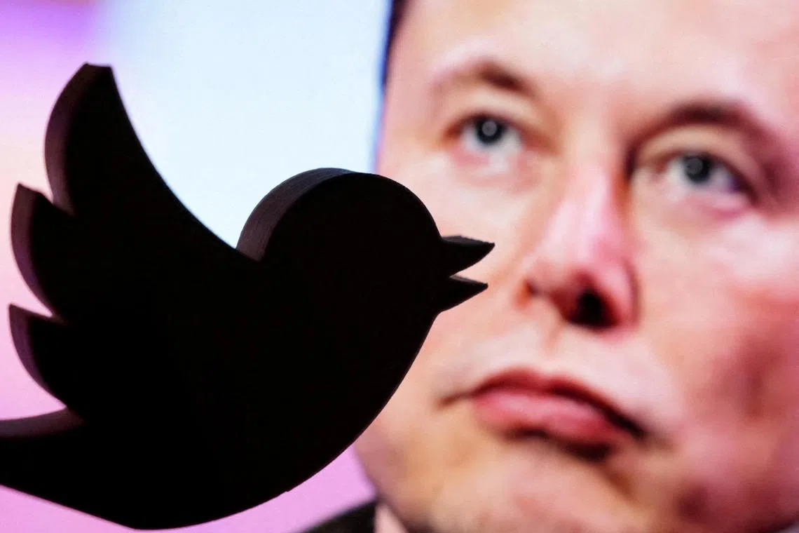 The Twitter logo is seen in front of a displayed photo of Elon Musk in this illustration.