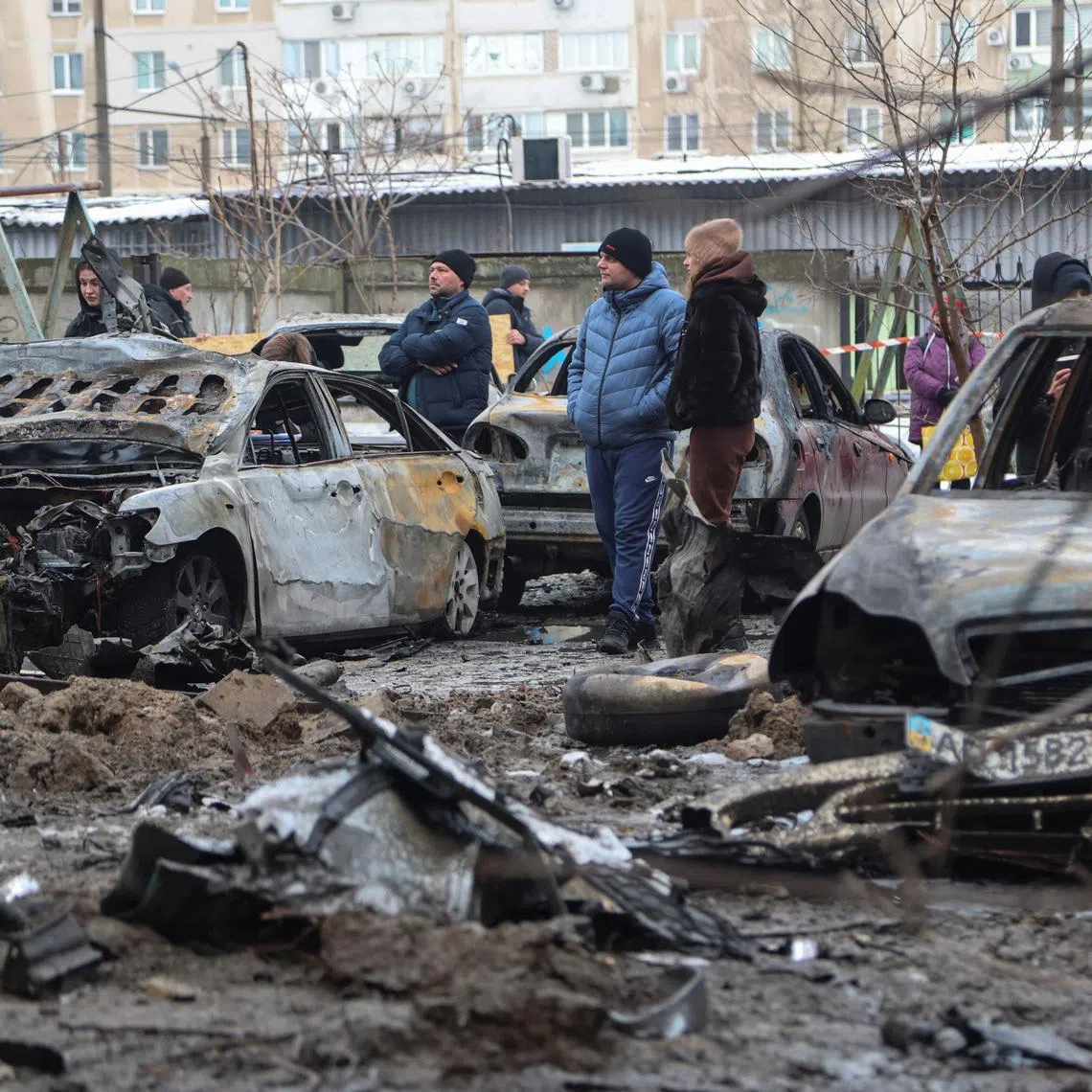 Residents stand next to burned cars at the site of an apartment building damaged during overnight Russian drone and missile strikes, amid Russia's attack on Ukraine, in Zaporizhzhia, Ukraine January 28, 2026. REUTERS/Serhii Chalyi