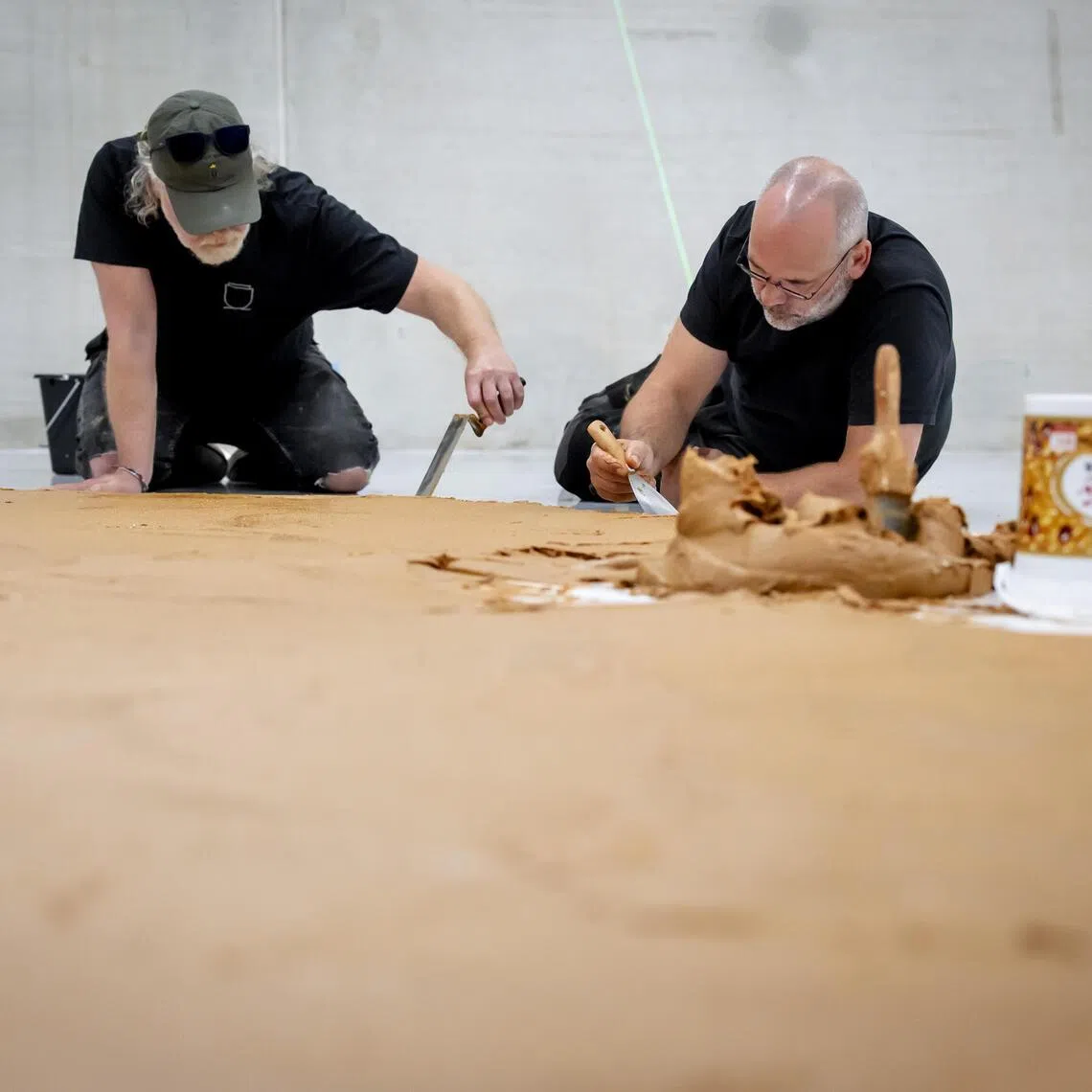 Two museum workers are spreading a floor of peanut butter, without chunks, in the Depot of Museum Boijmans Van Beuningen in Rotterdam on July 3.