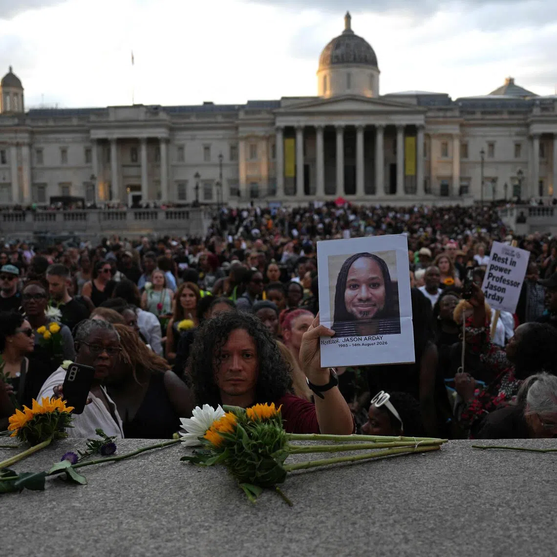 Supporters leave flowers and photographs after taking part in a vigil for the late Cambridge professor Jason Arday.
