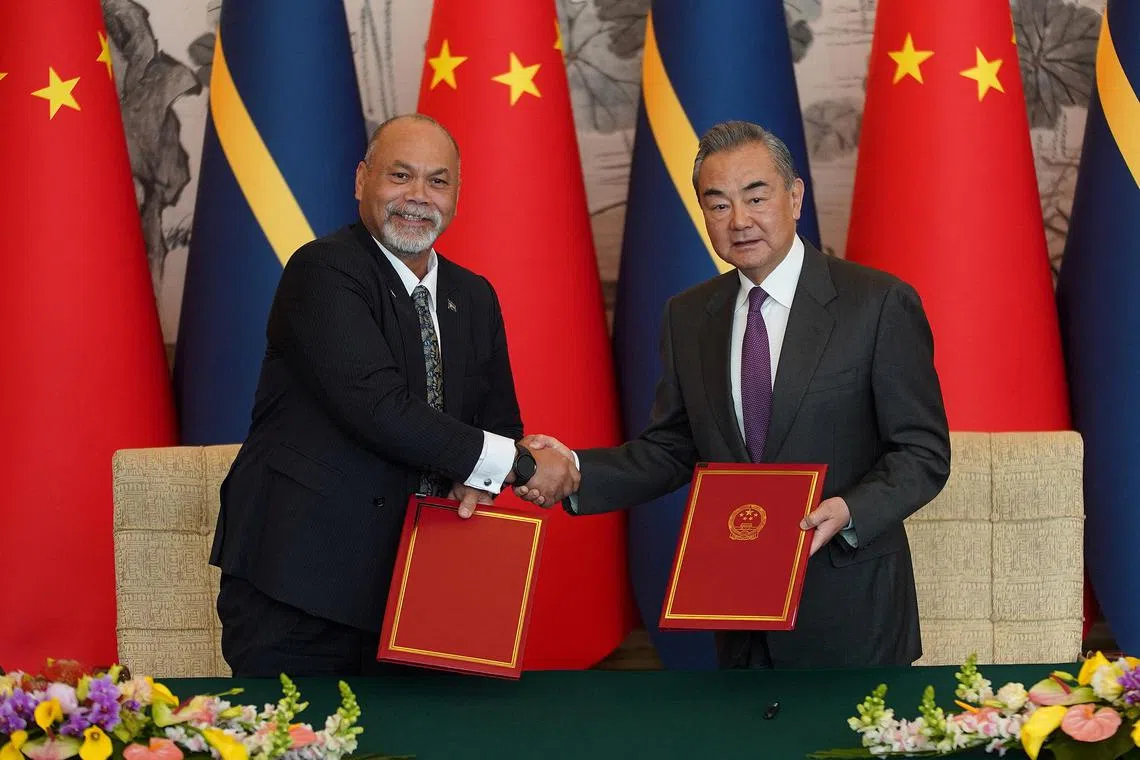 Chinese Foreign Minister Wang Yi (right) and Nauru Minister of Foreign Affairs and Trade of Nauru Lionel Aingimea shake hands after signing a joint communique on the Resumption of Diplomatic Relations between China and Nauru.