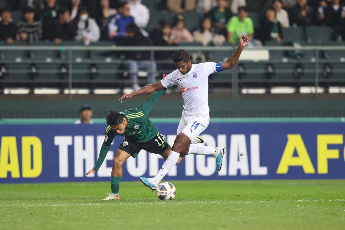 dgsoc25 - Hariss Harun (in white) winning the ball off Jeonbuk's Lee Dong-jun during the Lion City Sailors' 3-0 loss on Wednesday in the Asian Champions League


