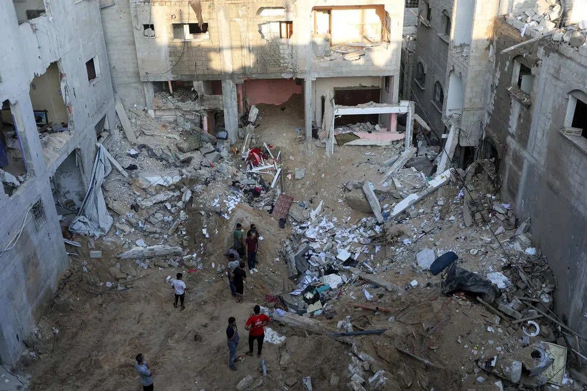 People survey the wreckage after an Israeli airstrike in Khan Younis, in southern Gaza, on Oct 12, 2023. 