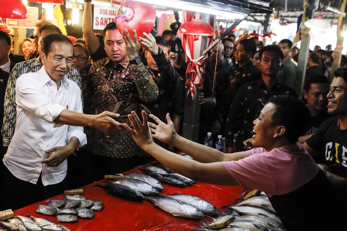 epa10678991 Indonesian President Joko Widodo (L) hands over a mobile phone after taking a selfie with an Indonesian worker living in Malaysia, during his visit to a wet market in Kuala Lumpur, Malaysia, 08 June 2023. Indonesian president Joko Widodo is on a two-day working visit to Malaysia at the invitation of the Malaysian Prime Minister Anwar Ibrahim.  EPA-EFE/FAZRY ISMAIL
