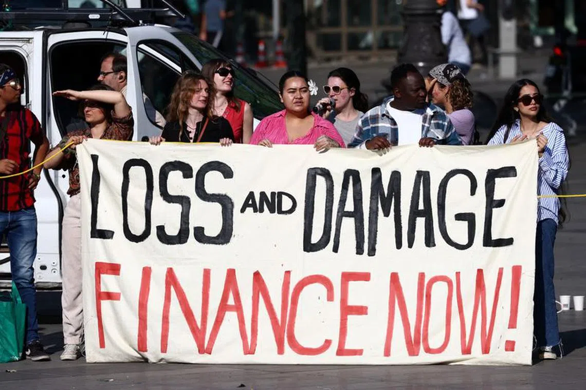 FILE PHOTO: Environmental activists hold a banner with the slogan \"Loss and damage, finance now\" during a climate strike action at the Place de la Republique, on the sidelines of the New Global Financial Pact Summit, in Paris, France, June 23, 2023. REUTERS/Stephanie Lecocq/File Photo