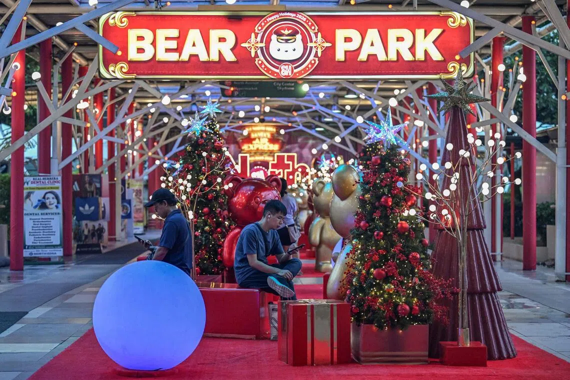 People resting beside Christmas decorations at a mall in Quezon City, Metro Manila.