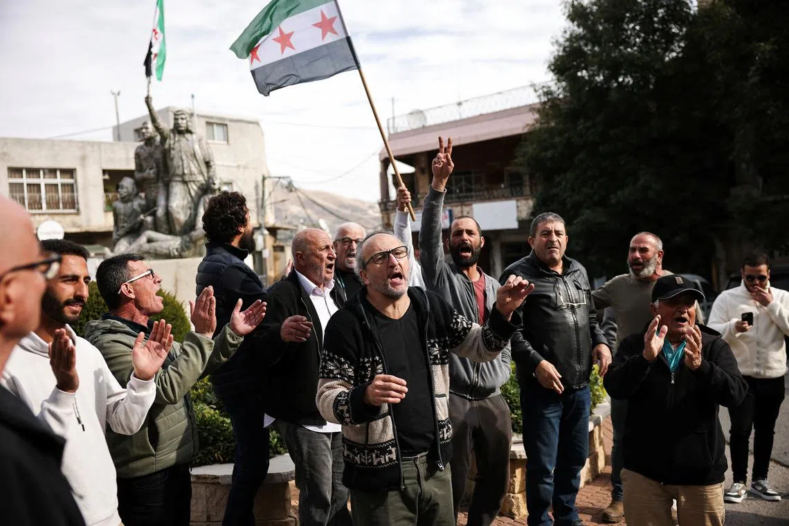 A person holds up a Syrian opposition flag, as people celebrate after Syrian rebels announced that they have ousted President Bashar al-Assad, in Majdal Shams, a Druze village in the Israeli-occupied Golan Heights, December 8, 2024. REUTERS/Stoyan Nenov