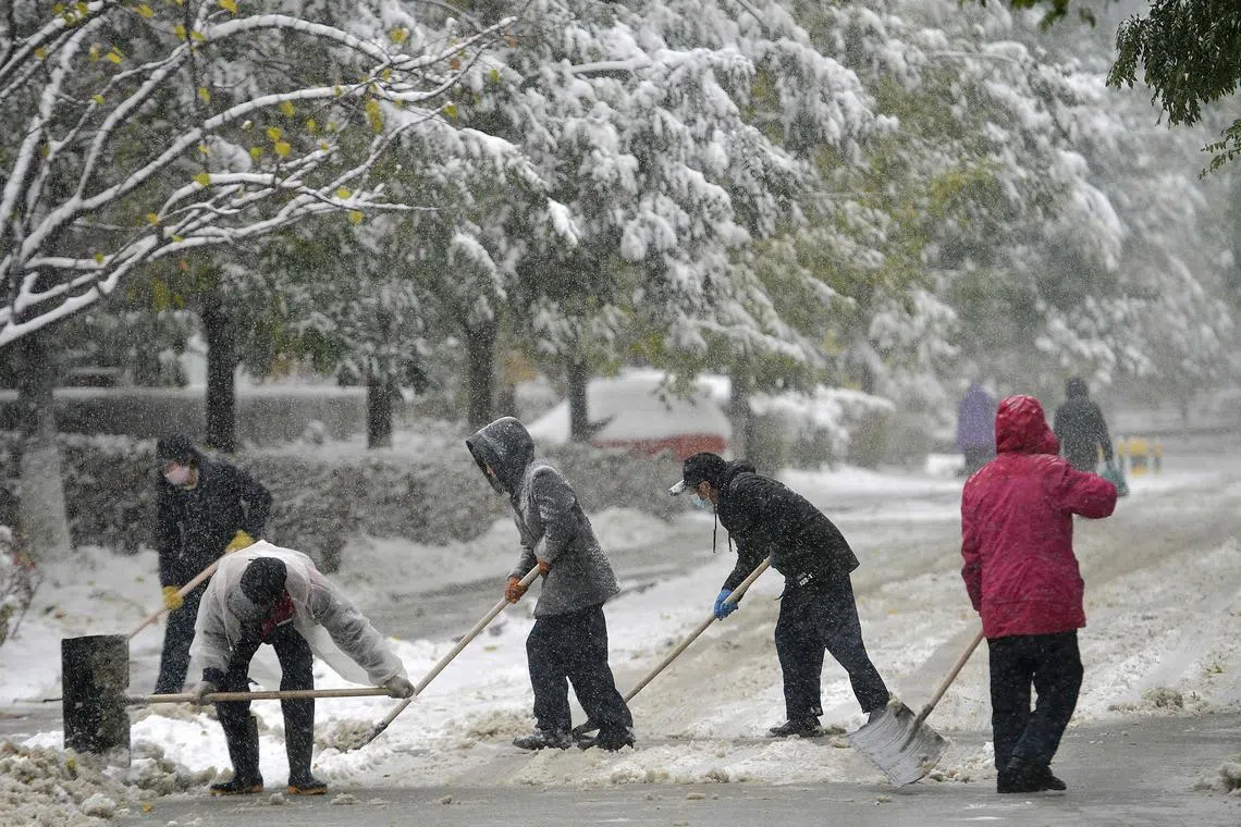 People shovel a street during snowfall in Shenyang, in China's northeastern Liaoning province on November 6, 2023. (Photo by AFP) / China OUT