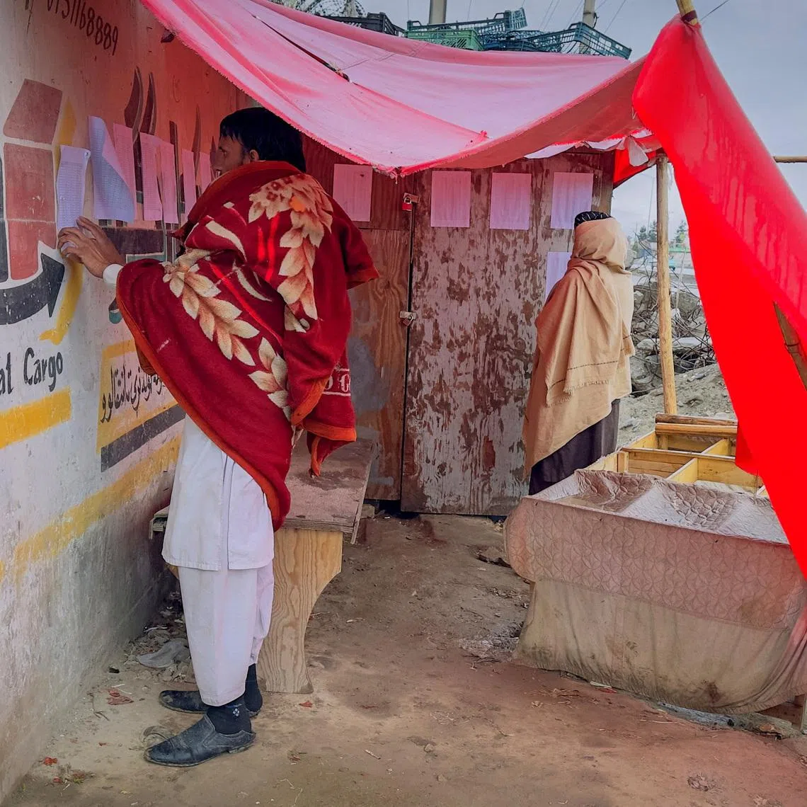 Afghan men search for the names of missing relatives on a list at the site of a drug rehabilitation center destroyed in what the Taliban said was a Pakistani airstrike in Kabul, Afghanistan, March 18, 2026.