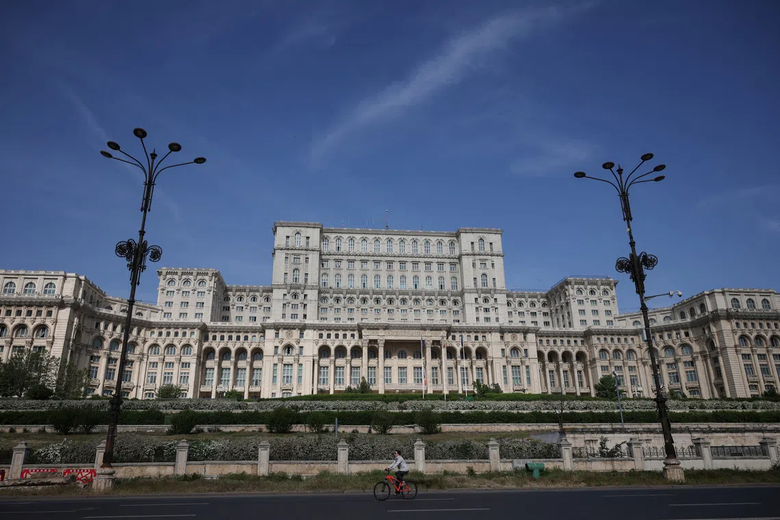 A person rides by the Palace of the Parliament in Bucharest, Romania, May 5, 2025. REUTERS/Louisa Gouliamaki