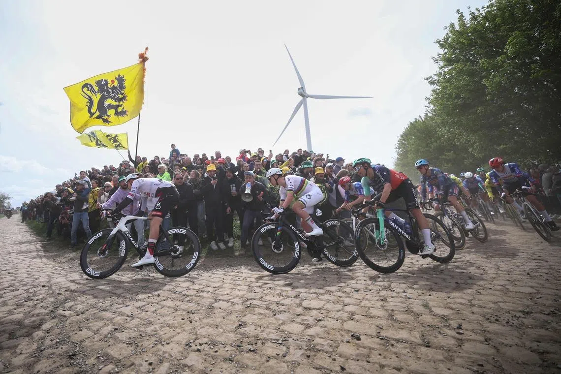 UAE Team Emirates XRG's Slovenian rider Tadej Pogacar (centre) riding with the pack on a cobblestone sector during the 123rd edition of the Paris-Roubaix one-day classic cycling race, in northern France, on April 12, 2026. 