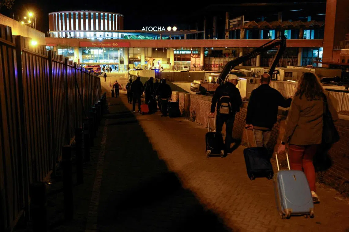 Travelers pull their luggage as they arrive to spend the night at the Atocha train station, following a massive power cut affecting the entire Iberian peninsula and the south of France, in Madrid on April 28, 2025. Spanish Prime Minister Pedro Sanchez said today authorities were not ruling out any  cause for the widespread blackout across the Iberian pensisula. "All potential causes are being analysed, I insist, without ruling out any hypothesis, any possibility," Sanchez told a press conference, 11 hours after Spain and Portugal were  plunged into darkness for reasons that had yet to be determined. (Photo by OSCAR DEL POZO / AFP)