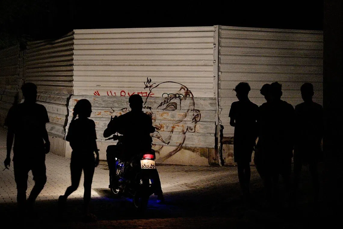 People is silhouetted against the light of a motorbike during the second day of the nationwide blackout in Havana on Oct 19, 2024. 