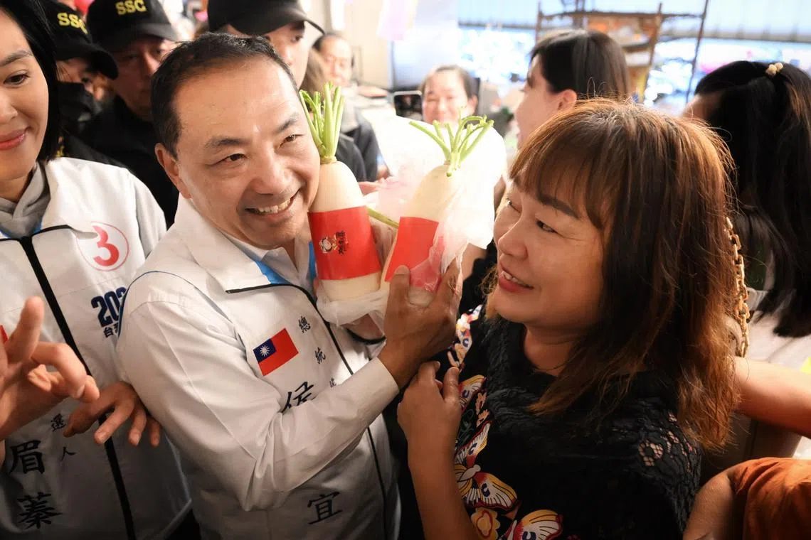Hou Yu-ih, the KMT presidential candidate, presented with white turnips during a visit to a market in Kaohsiung on Jan 10, 2024.