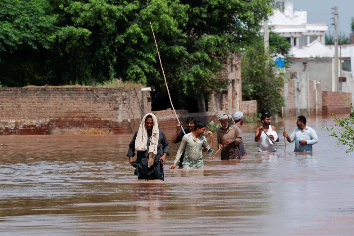 Residents wade through a flooded road, following monsoon rains and rising water levels in Qadirabad village near the Chenab River in Punjab province, Pakistan August 28, 2025. REUTERS/Akhtar Soomro
