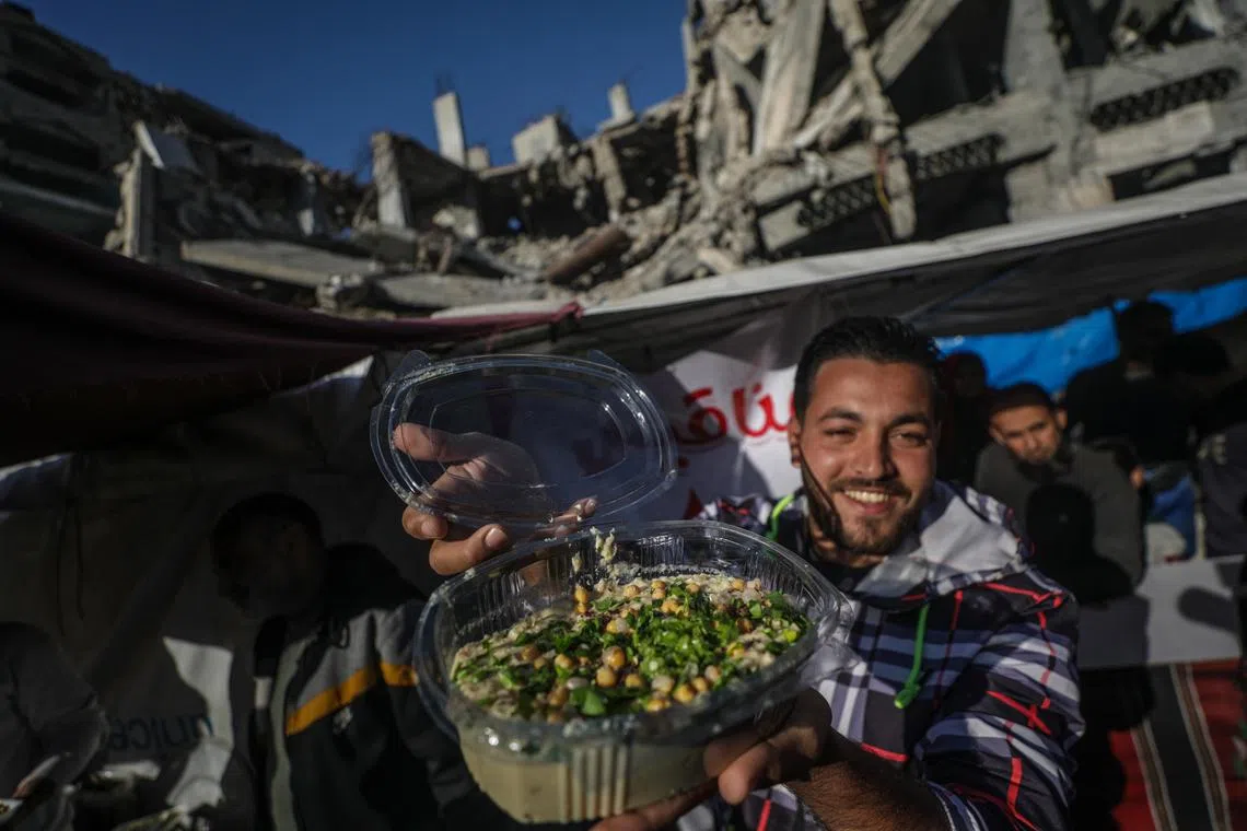 A Palestinian vendor displaying hummus next to a destroyed house on the first day of Ramadan, Gaza Strip, on Mar 11, 2024. 