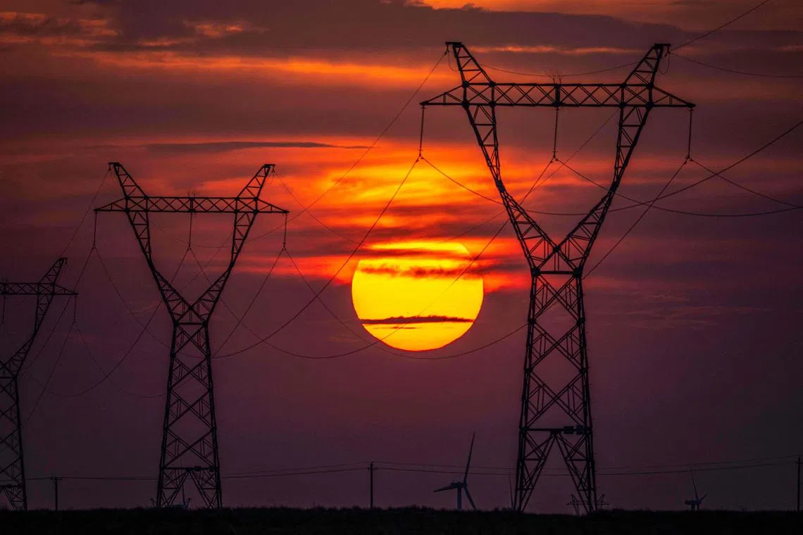 The sun sets behind electrical transmission towers in Tongliao in northern China's Inner Mongolia region on July 22, 2024. (Photo by AFP) / China OUT