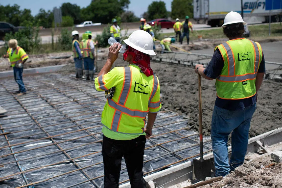 A construction worker takes a sip of water while repairing a road that was damaged from the heat in Houston, Texas, on June 27, 2023.