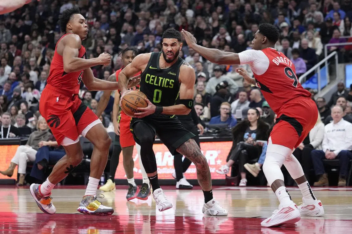 Boston Celtics forward Jayson Tatum drives against Toronto Raptors forward Scottie Barnes and guard RJ Barrett during the first half at Scotiabank Arena.