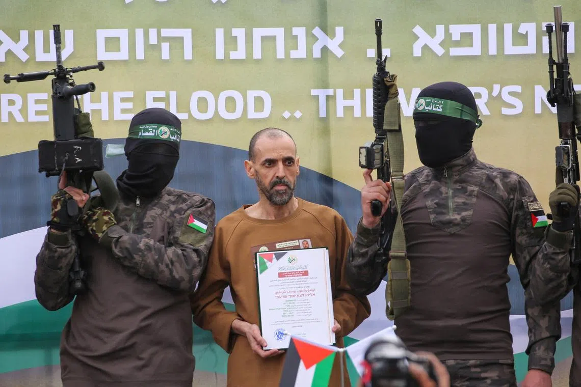 Israeli hostage Eli Sharabi on a stage in Central Gaza before being handed over by Hamas fighters to Red Cross officials, on Feb 8.