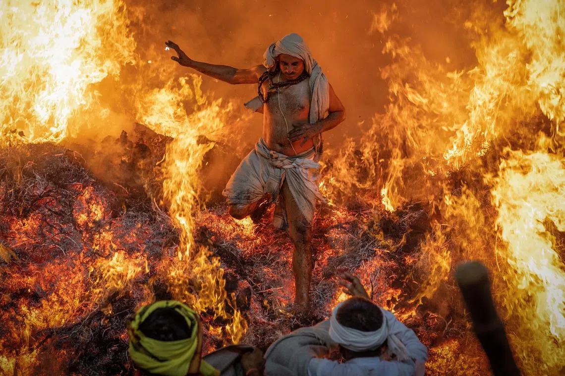 A Hindu priest  jumping out of a fire during a ritual known as "Holika Dahan," which is part of the Holi festival celebrations, at village Phalen near the northern Indian city of Mathura, India, on Mar 14, 2025. 