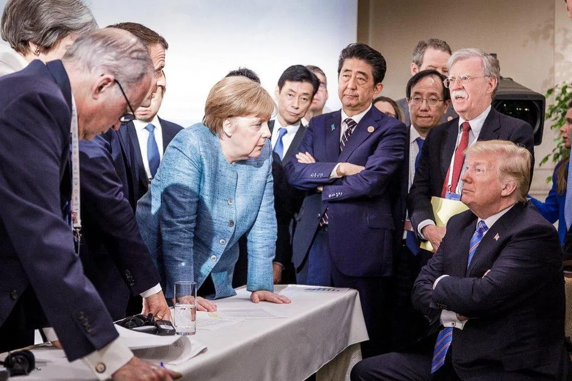 Then German Chancellor Angela Merkel defiantly confronting then US President Donald Trump at the 2018 summit of the Group of Seven industrialised nations in Canada, while surrounded by other G-7 leaders.