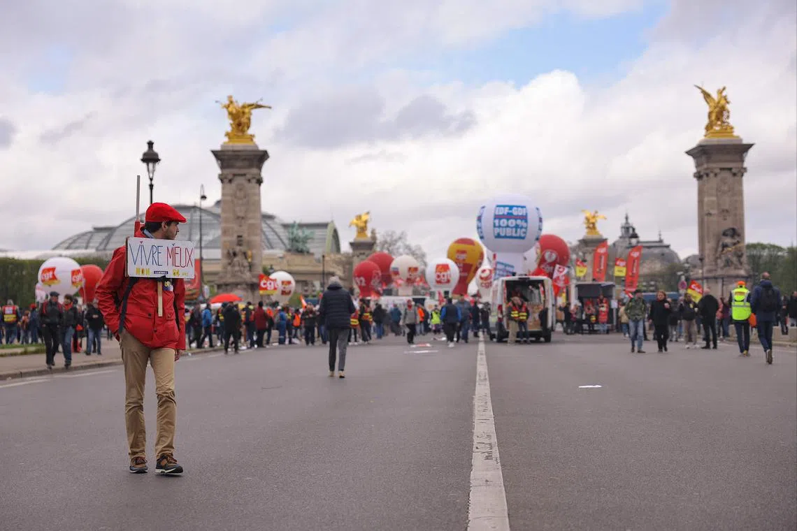 A demonstrator with a placard that reads "Live better, no to retiring at 64 years" during a protest against pension reforms, in Paris on April 6.