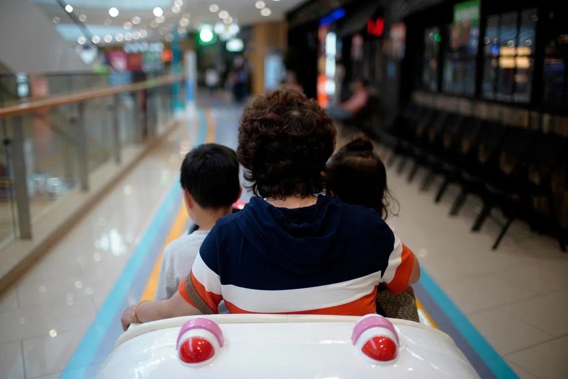 FILE PHOTO: A person sits in a toy car with children at a shopping mall in Shanghai, China June 1, 2021. REUTERS/Aly Song/File Photo
