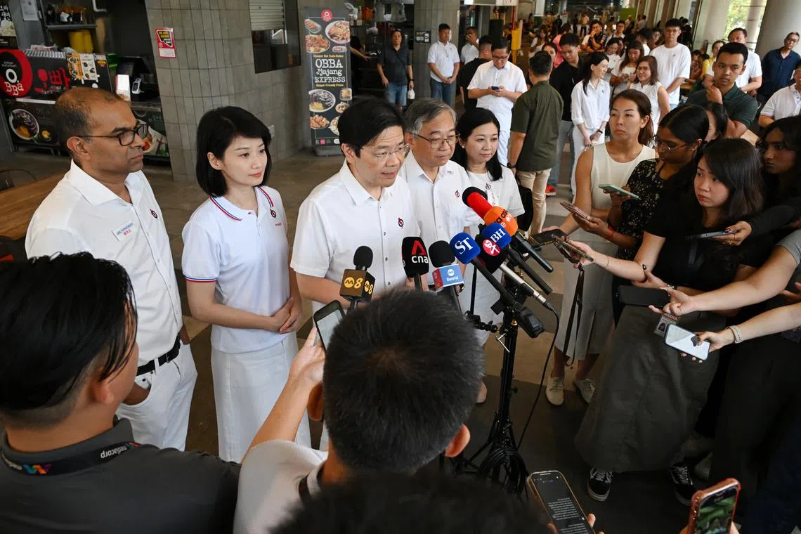 PM Lawrence Wong (centre), flanked by the PAP's Punggol GRC candidates (from left) Janil Puthucheary, Sun Xueling, Gan Kim Yong and Yeo Wan Ling, speaking to the media on the sidelines of a walkabout at the One Punggol Hawker Centre on April 29.