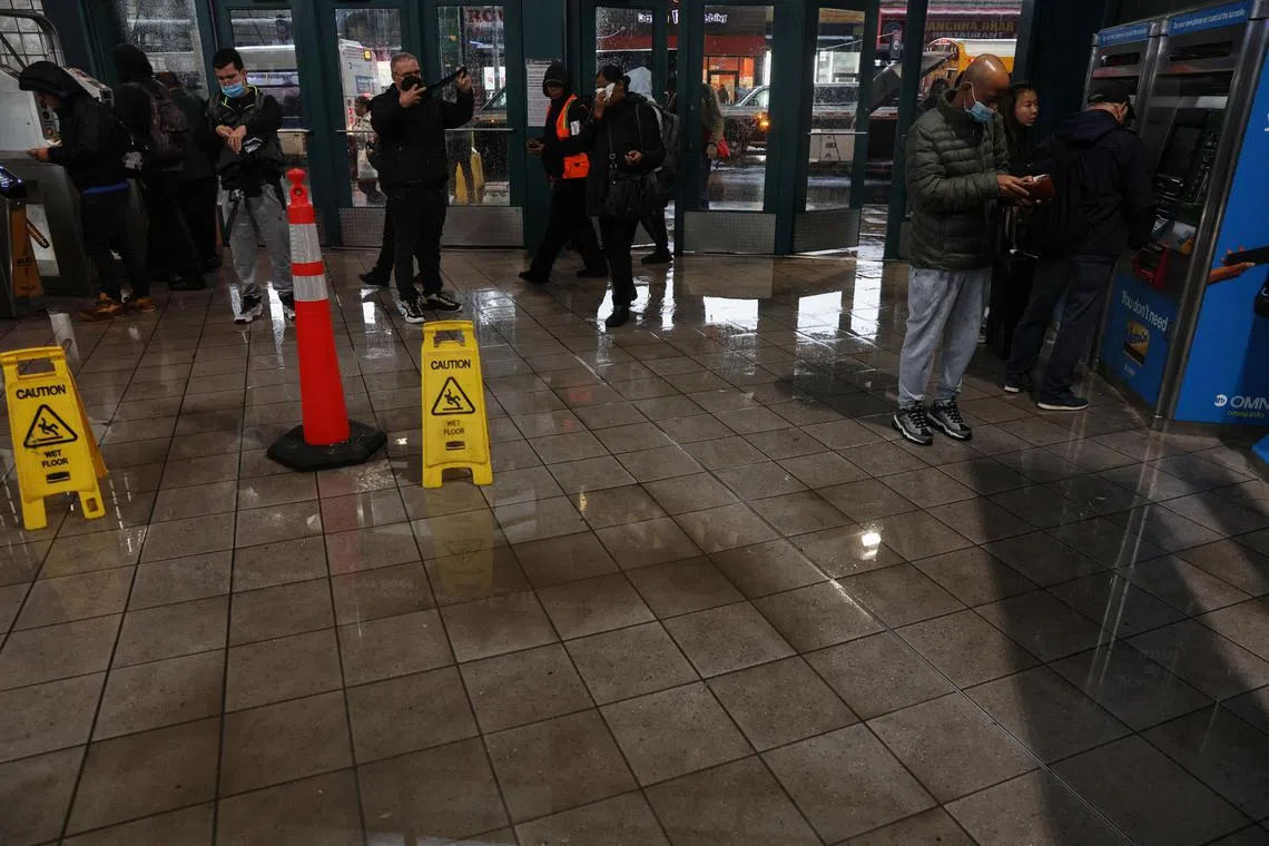 People enter a wet lobby of the Jackson Heights–Roosevelt Avenue/74th Street station, after heavy rains, in the Queens borough of New York City.
