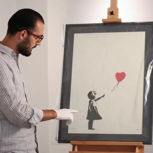 Gallery manager Lindor Mehmetaj with the print of Banksy's "Girl with Balloon", after it was returned to the London gallery.