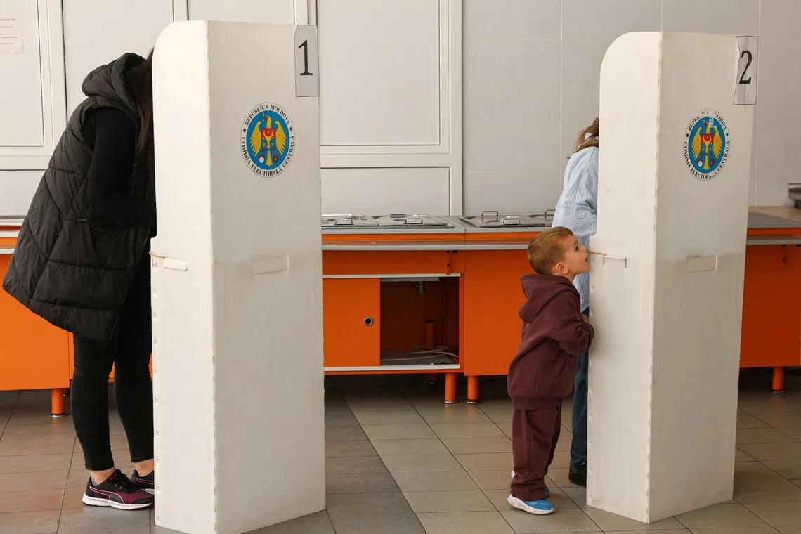 FILE PHOTO: A child stands next to a voting booth, as people vote at a polling station during Moldova's parliamentary elections in Chisinau, Moldova September 28, 2025. REUTERS/Vladislav Culiomza/File Photo