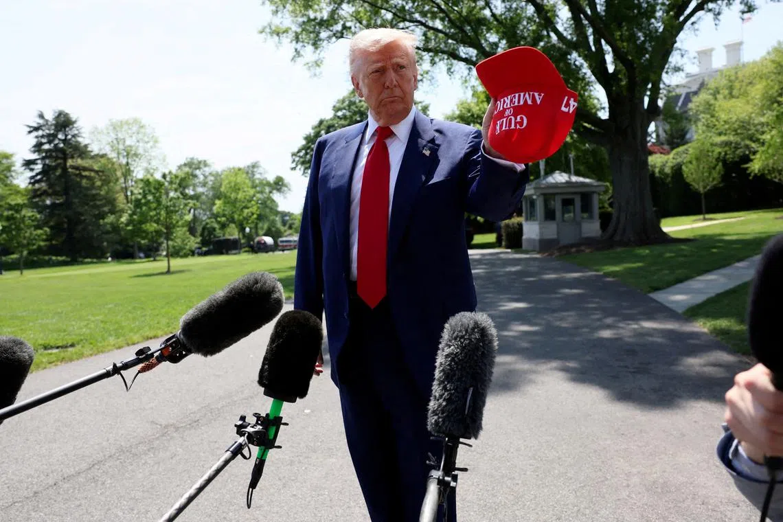 U.S. President Donald Trump holds a cap with the words \"Gulf of America\" embroidered as he speaks to the media before boarding Marine One to depart for Michigan to attend a rally to celebrate his first 100 days in office, from the South Lawn of the White House in Washington, D.C., U.S., April 29, 2025. REUTERS/Leah Millis