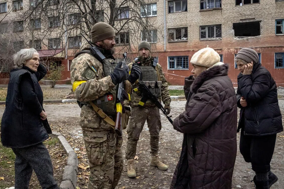 Ukrainian servicemen speak to local residents after Russia's military retreat from Kherson, on Dec 1, 2022.