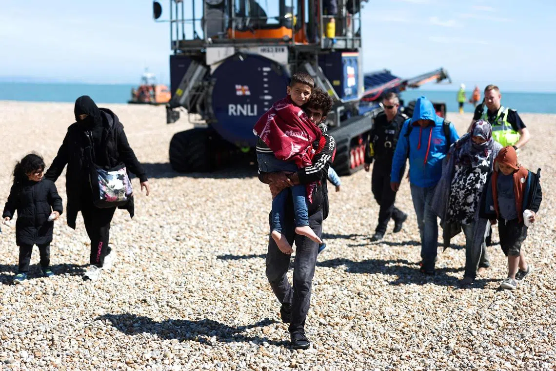 Migrants at England's Dungeness beach on Aug 16 after disembarking from a lifeboat while crossing the English Channel from France.