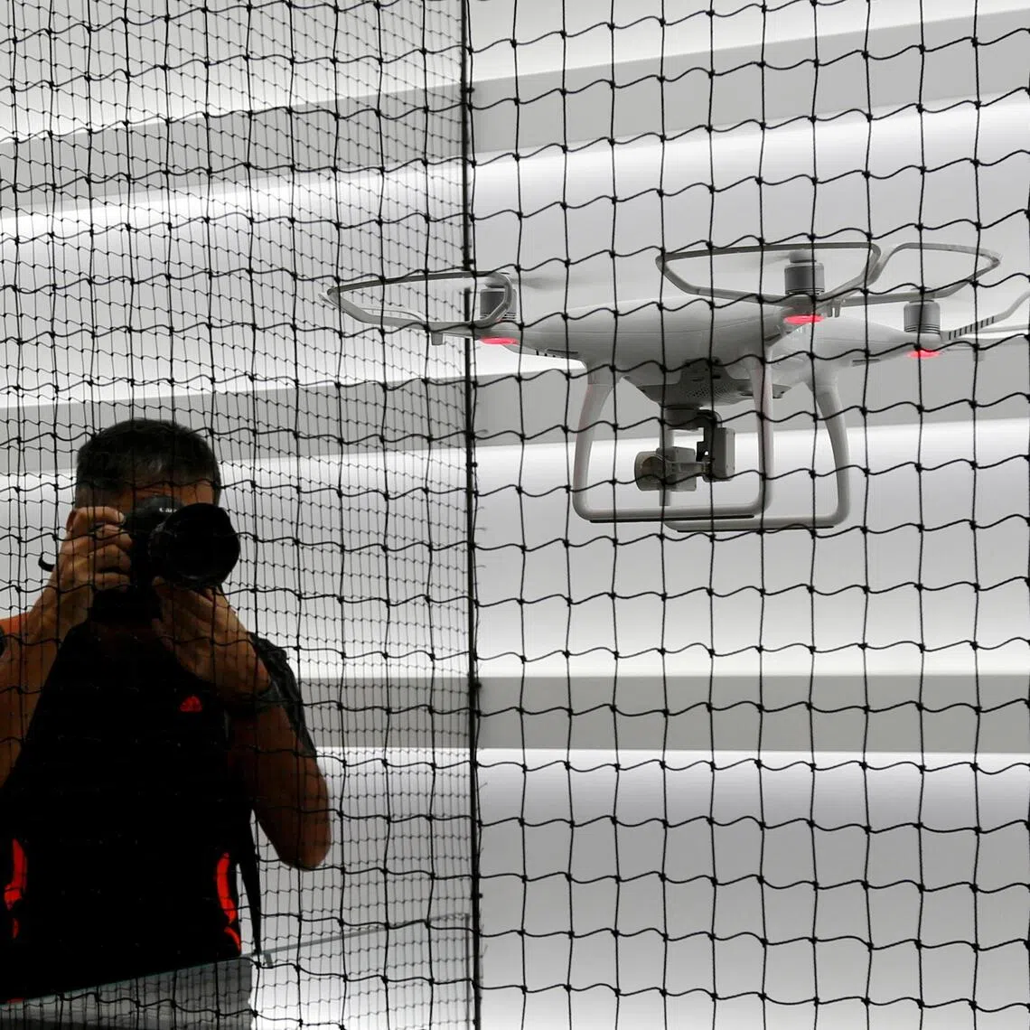 FILE PHOTO: Photographers take photos of a drone flying at DJI's flagship store in Hong Kong, China September 22, 2016, two days before its opening. REUTERS/Bobby Yip/File Photo