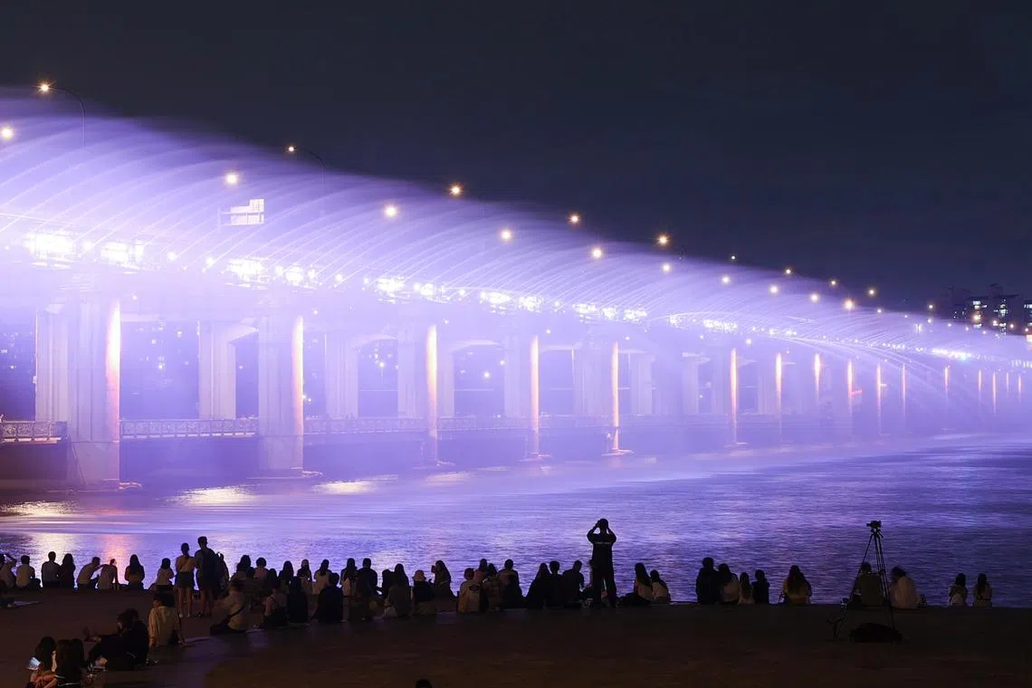 The Banpo Bridge Rainbow Fountain over the Han River in Seoul is lit  up in purple on the night of June 12, 2023, as part of a two-week festival to celebrate the tenth anniversary of global K-pop sensation BTS' debut, which falls on June 13.  