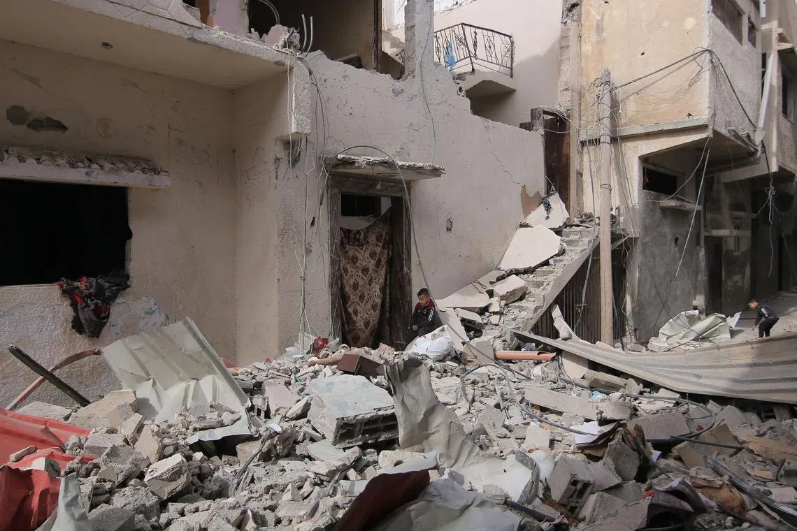 A Palestinian child sits amongst the rubble of a destroyed building in Rafah, southern Gaza Strip, on Feb 12.