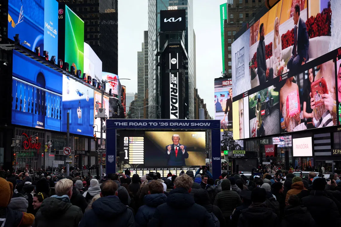 People watch as U.S. President Donald Trump draws USA during the FIFA World Cup 2026 Draw on a screen in Times Square in New York City, U.S., December 5, 2025.  REUTERS/Brendan McDermid      TPX IMAGES OF THE DAY