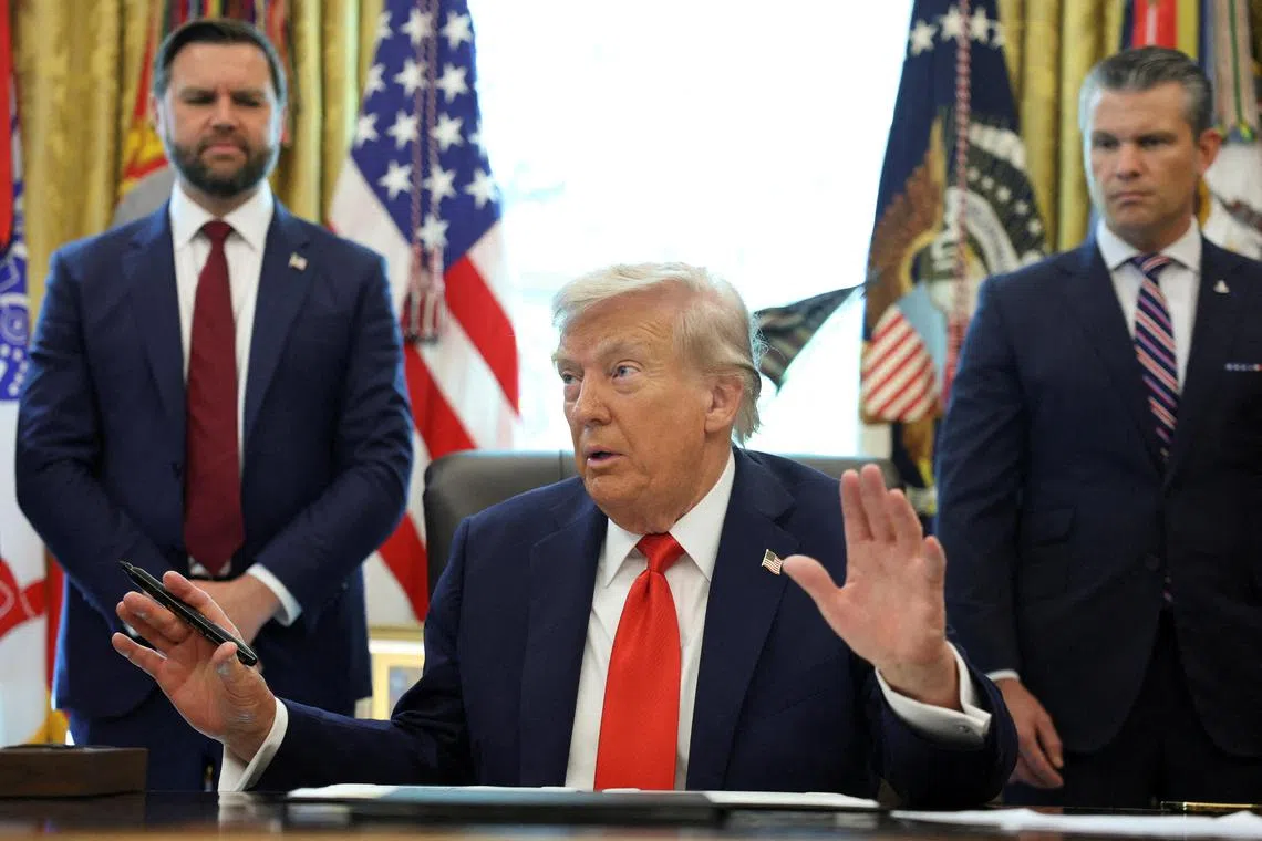 US President Donald Trump signing an executive order on Aug 25, flanked by Vice-President J.D. Vance (left) and Defence Secretary Pete Hegseth.