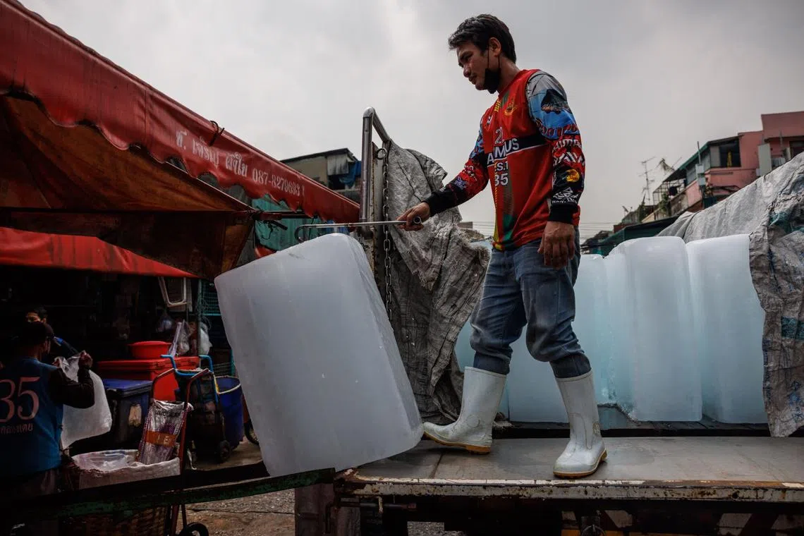 A worker unloads a block of ice at a wet market during a heat wave in Bangkok, Thailand, on April 27, 2023.