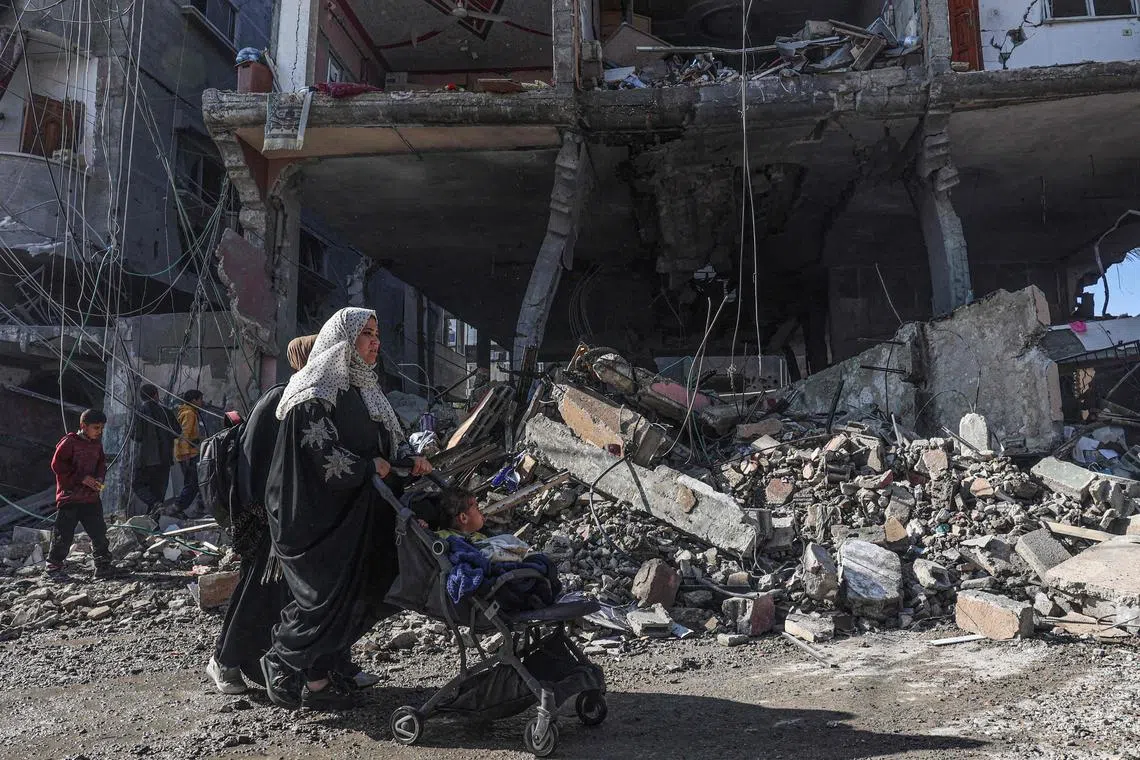 Palestinians walk past building rubble following Israeli air strikes on the Rafah refugee camp in the southern Gaza Strip on Feb 24.