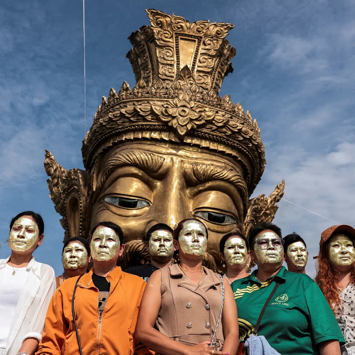 Devotees with their faces covered in gold leaves pose for a picture in front of a statue of Por Kae during a "Na Na Thong", or Gold Leaf Face-Blessing ritual, a sacred ritual believed to enhance wealth and fortune, at a shrine in Ayutthaya province, Thailand, August 30, 2026. REUTERS/Chalinee Thirasupa     TPX IMAGES OF THE DAY