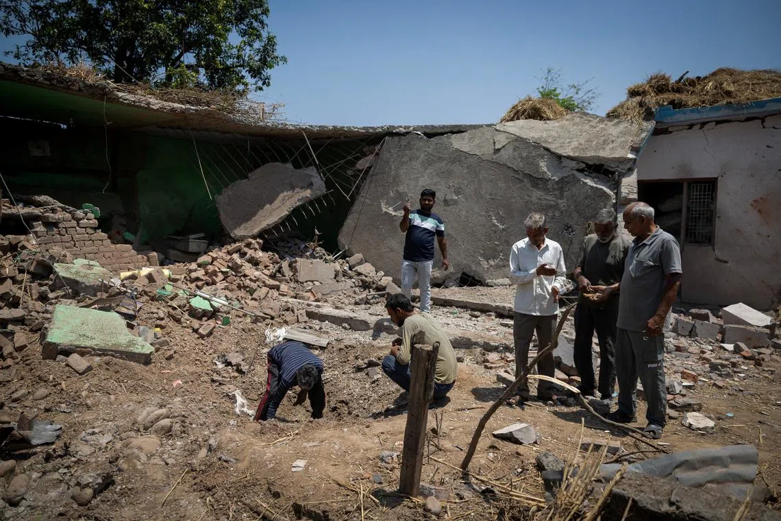 Villagers look for the fragments in a crater outside a house damaged by a cross-border shelling last week at Kot Maira, a border village in Jammu region, May 12, 2025. REUTERS/Adnan Abidi