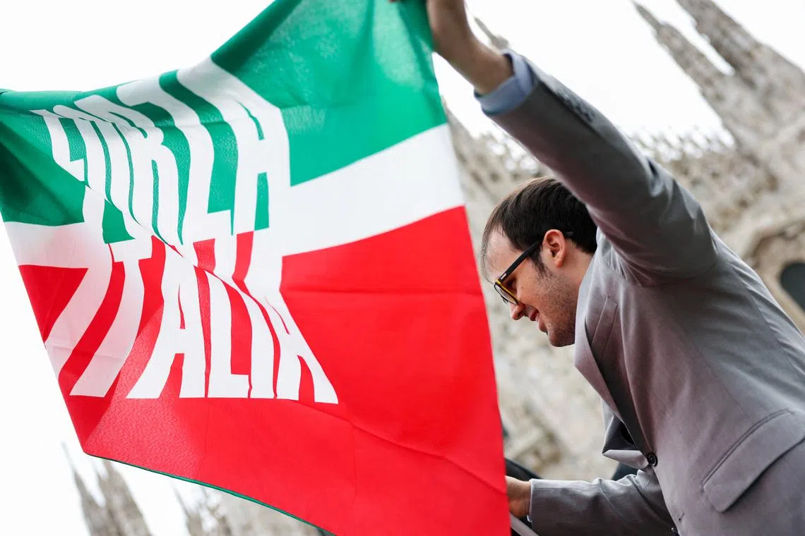 A man with Forza Italia flag stands outside the Duomo Cathedral following the death of former Italian Prime Minister Silvio Berlusconi, in Milan, Italy June 14, 2023. REUTERS/Claudia Greco/File Photo