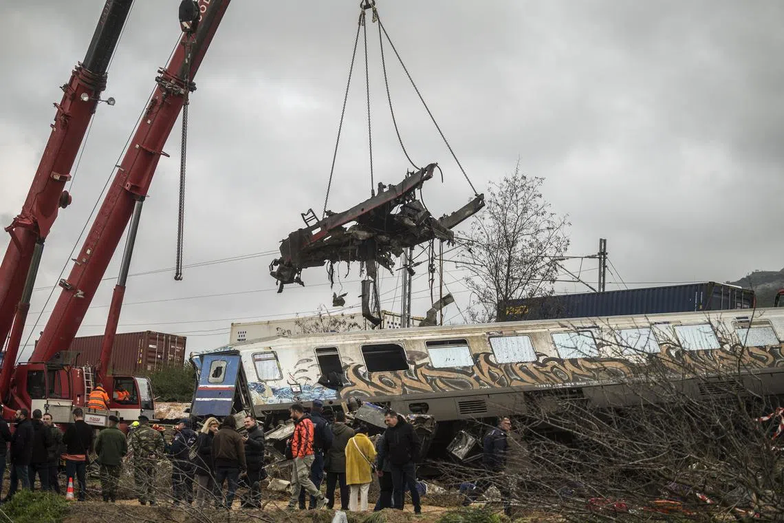 A crane is used to clear wreckage at the site of a crash in Greece between a freight train and a passenger train carrying over 350 people.